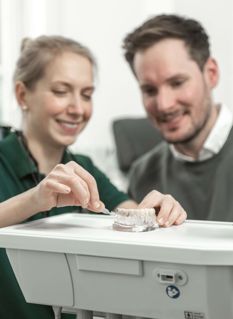 Ärztin zeigt Patient die richtige Zahnreinigung